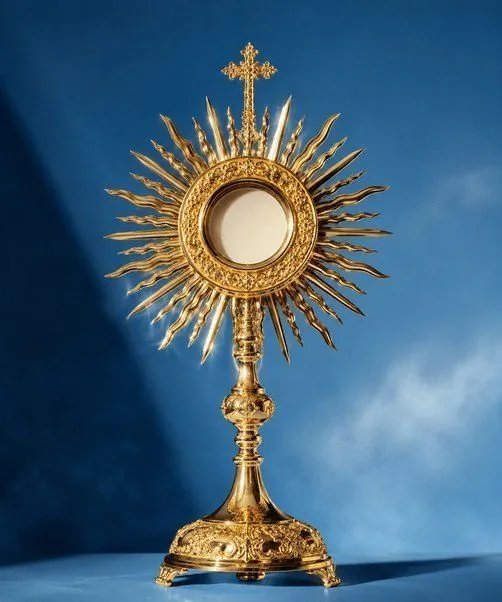 Gold monstrance with a radiant sunburst against a blue backdrop