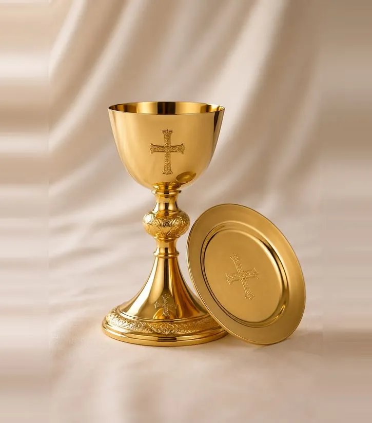 Gold chalice and paten held before an embroidered vestment
